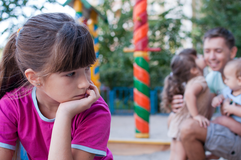 Girl sad because of jealous younger sister to father