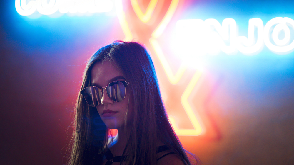 Girl in sunglasses on a neon background in the club