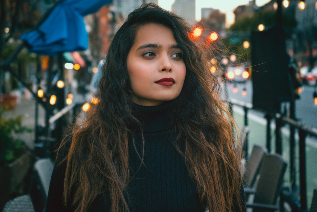 a woman with long hair standing on a city street