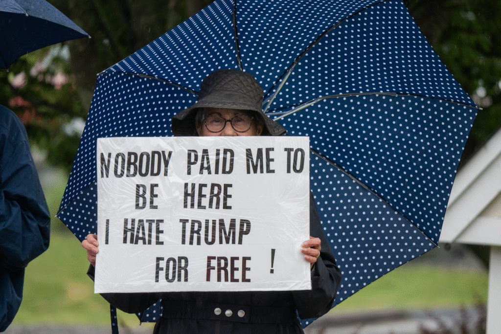 A senior woman holding up a sign in opposition to Trump