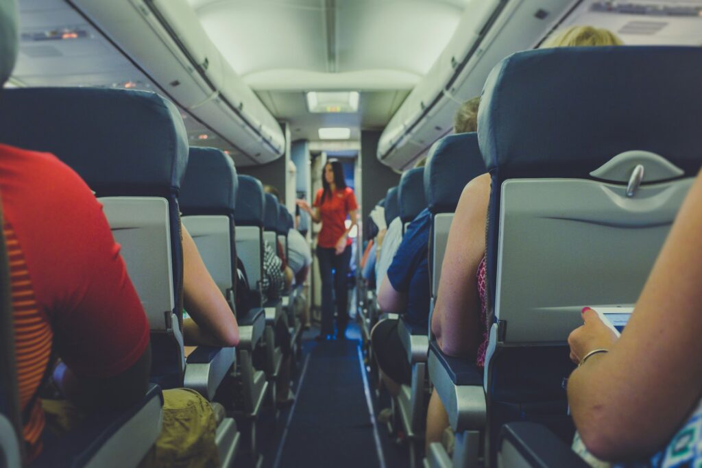 flight attendant standing between passenger seat
