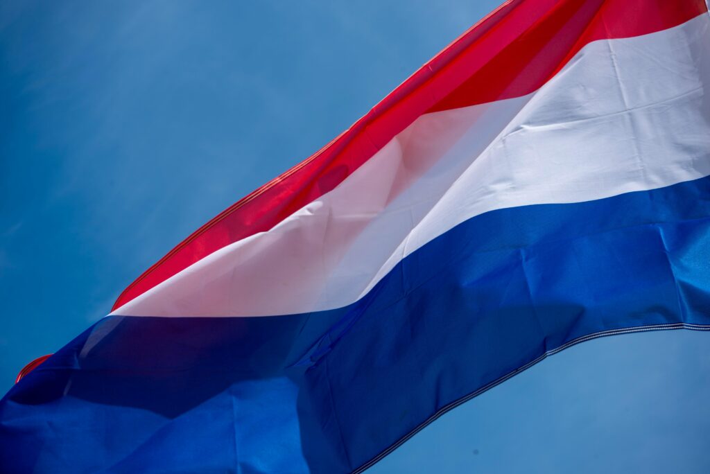 Vibrant Netherlands Flag Waving Against Blue Sky
