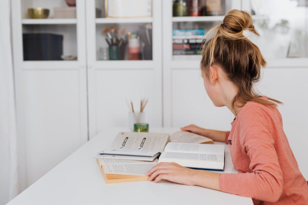 Girl in Pink Long Sleeve Shirt Reading a Book
