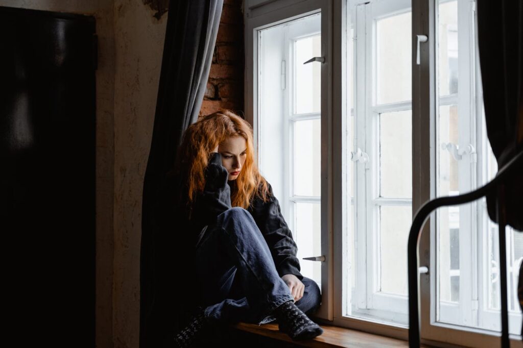 Woman in Black Leather Jacket Sitting on Brown Wooden Floor
