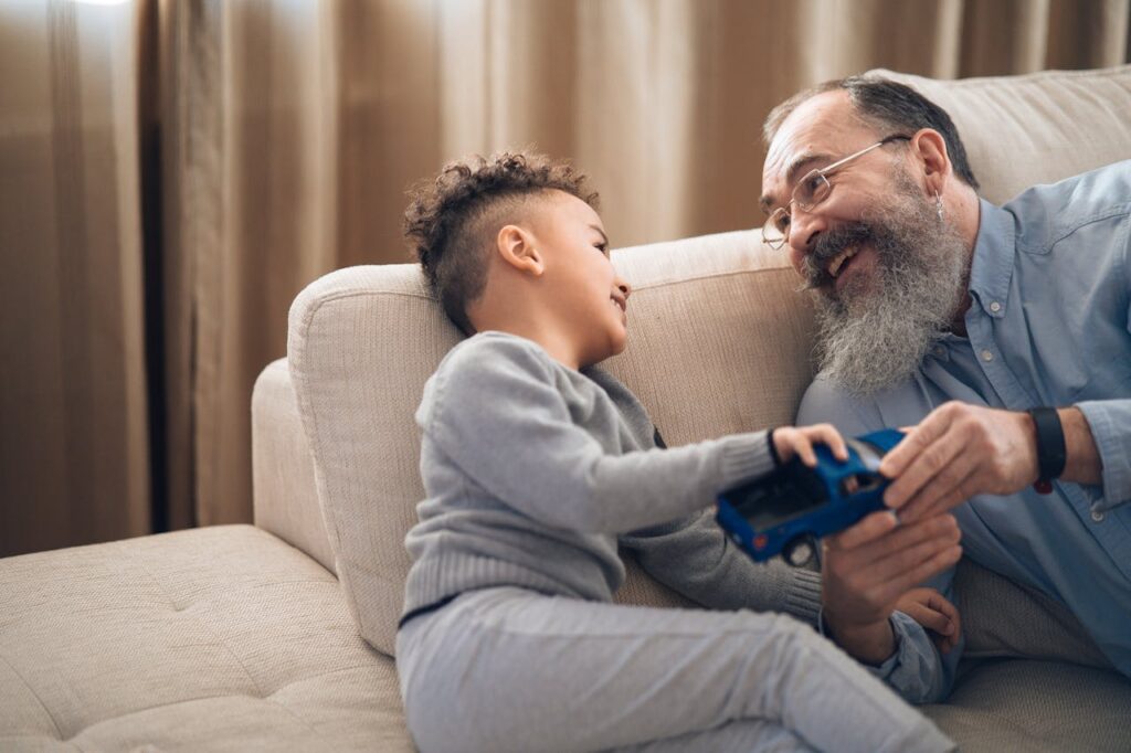 boy with his grandfather playing with blue toy truck