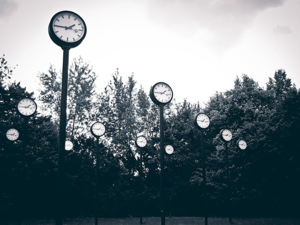 Gray Scale Photography of Clock Near Trees
