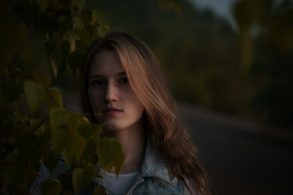 woman in white shirt standing beside green plant during daytime