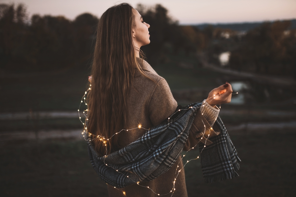 Portrait of girl with light LED garland outdoor holds a lightes. Fairy illumination winter christmas mood. Selected focus