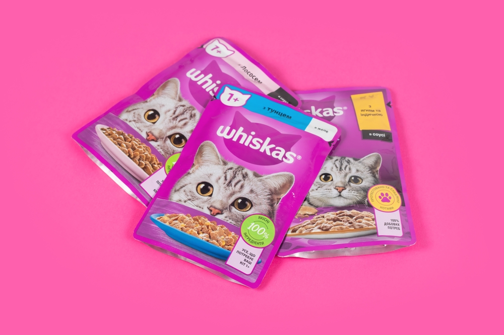 Dnipro, Ukraine - August 04, 2023: Various Whiskas cat food ready for sale on pink background. Cat food as background
