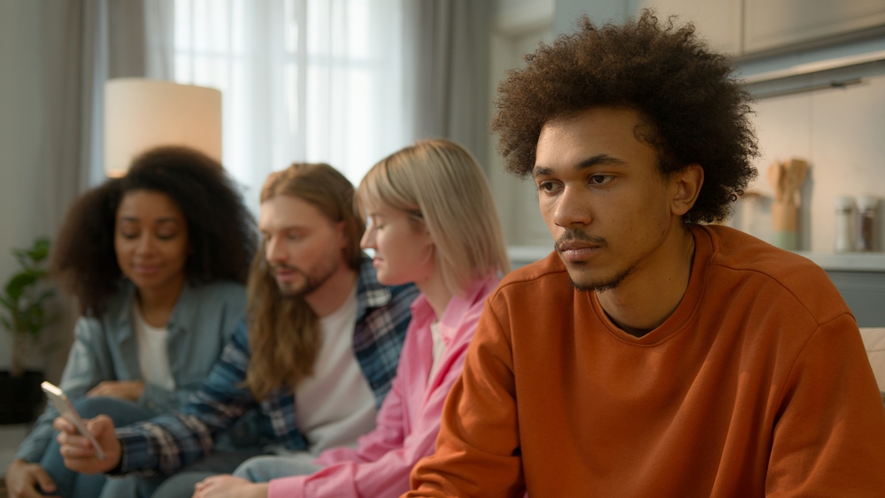 African American sad pensive thinking troubled problem frustrated man guy male at home separated ignore multiracial Caucasian multiethnic friends women men mobile phone using addicted laughing talking