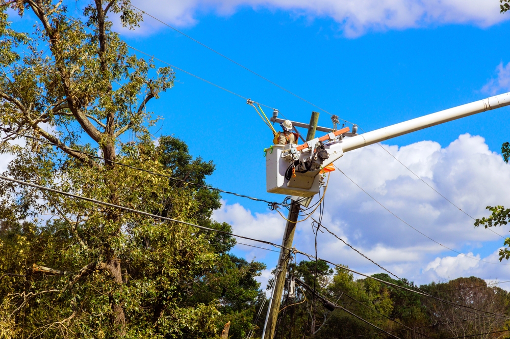 Utility tower truck is being used by emergency service linemen to perform repairs to power electrical lines damaged by storm hurricane