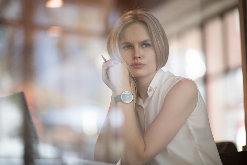 Thoughtful concept. Woman working on a computer at a cafe while gazing through the window glass.