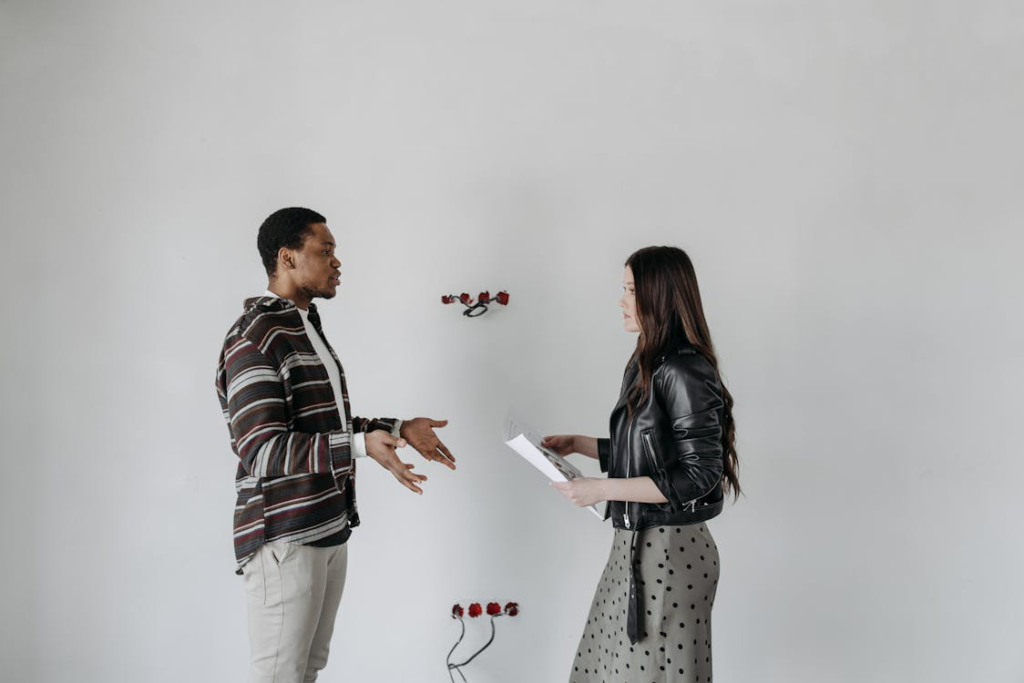 Married Couple Talking While Standing Beside White Wall