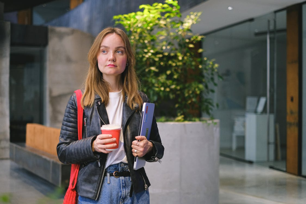 Young Woman with Coffee and Laptop in Modern Space