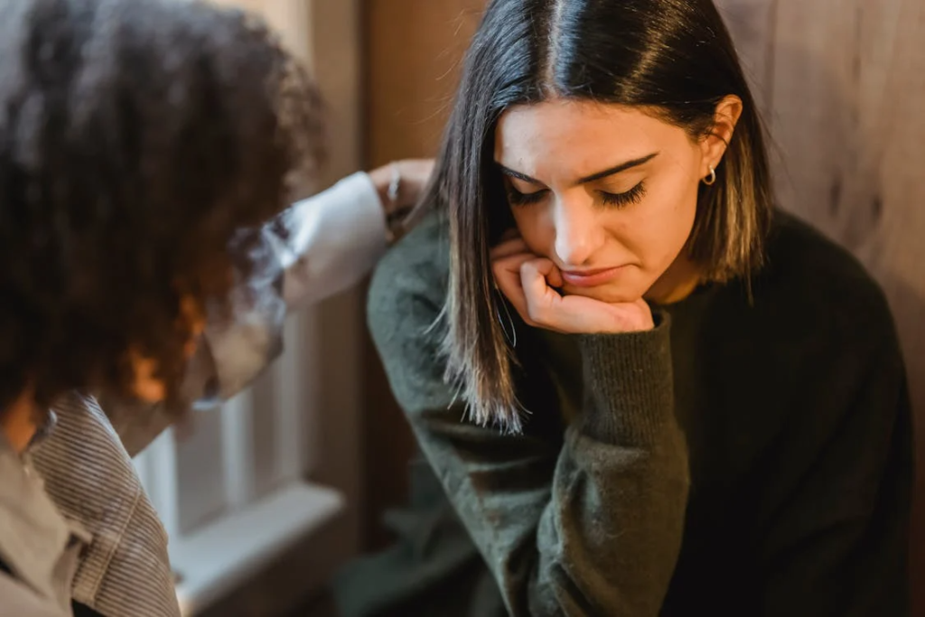 Crop woman tapping shoulder of frustrated female friend
