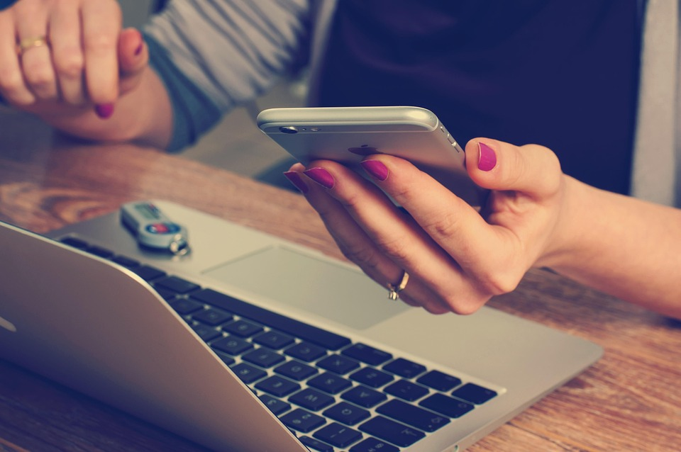 Person staring at phone and laptop on a desk