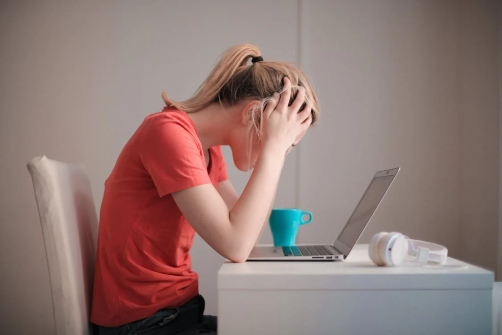 person sitting at a desk with their hands on head