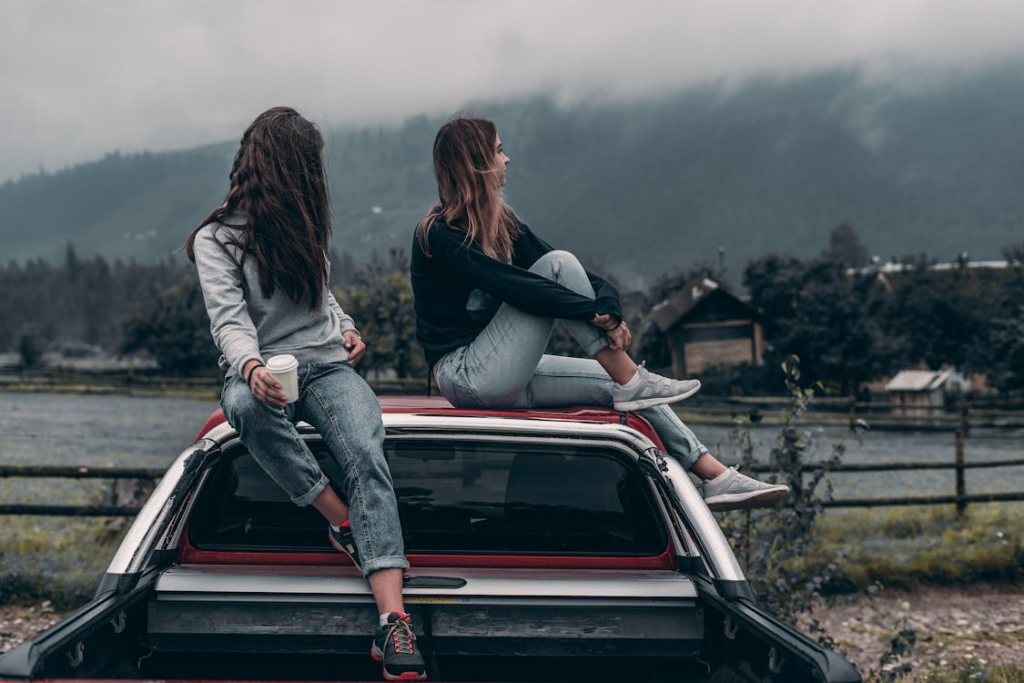 Two friends sitting on the roof of a truck.