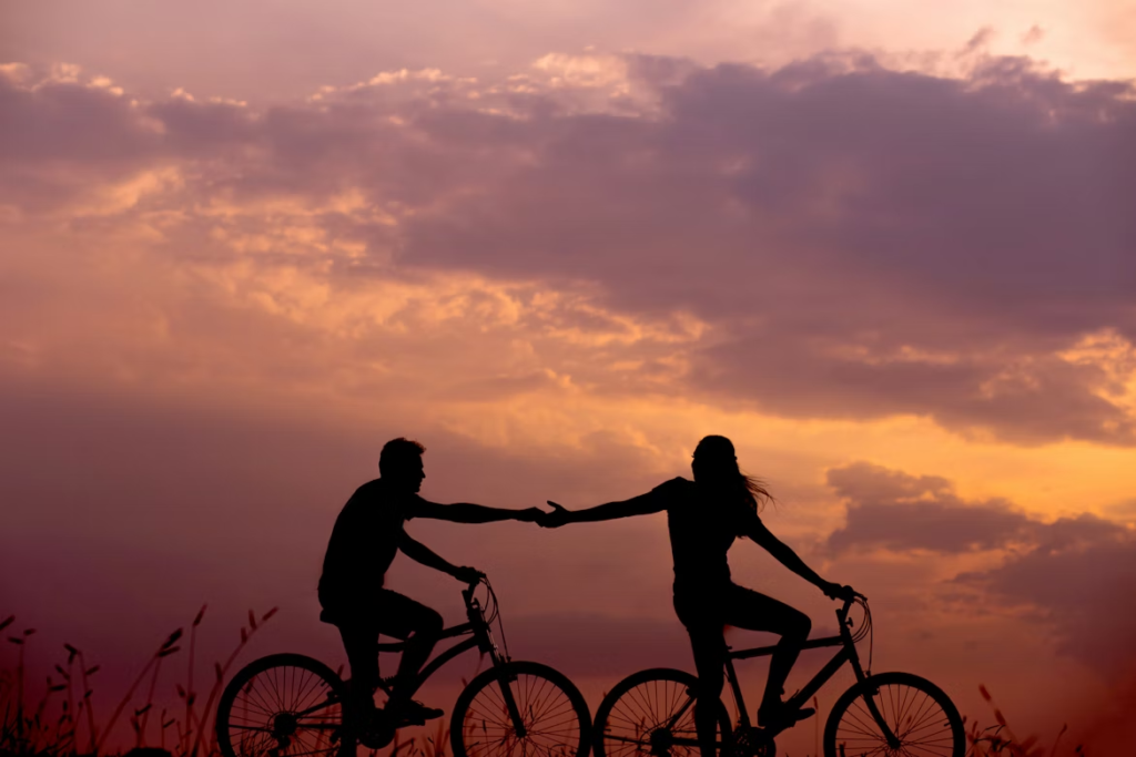 Two people riding bicycles in the sunset.
