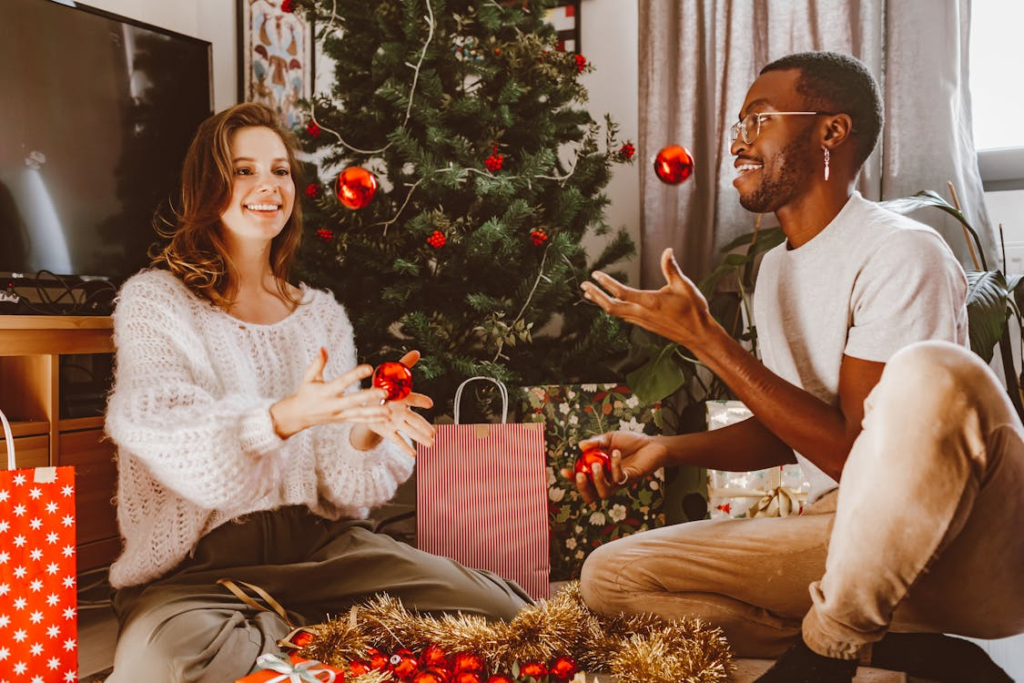 Man and woman in front of a Christmas tree unwrapping gifts
