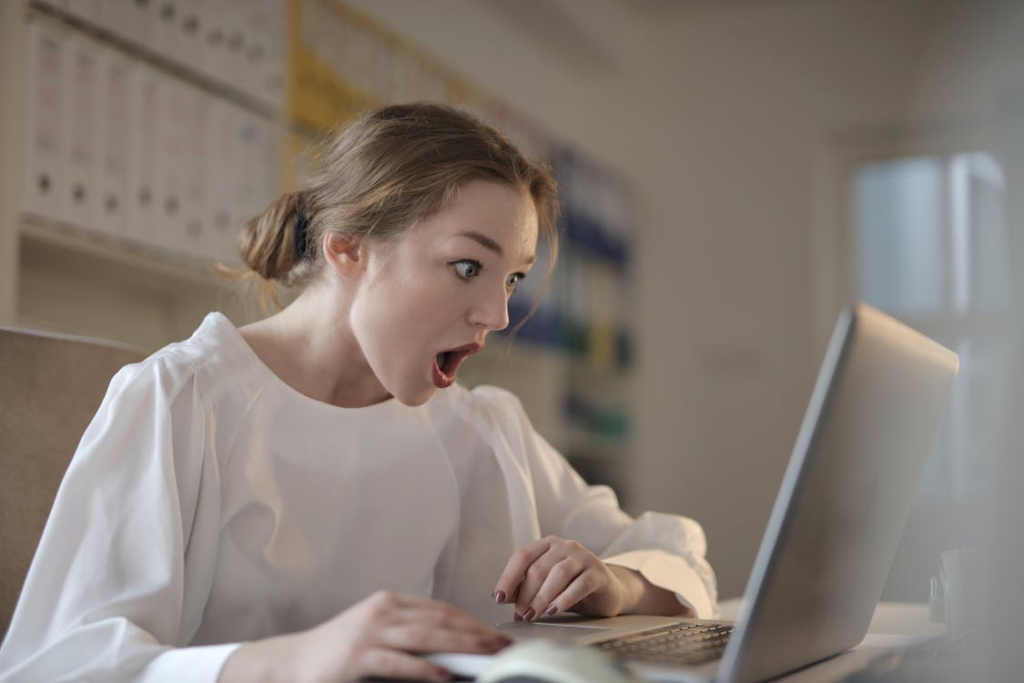 Woman staring at laptop screen with a surprised expression.