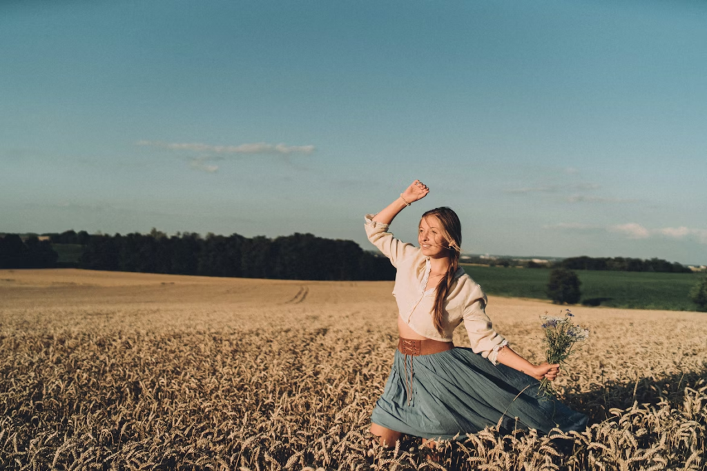 a-woman-standing-in-a-field-with-her-arms-in-the-air