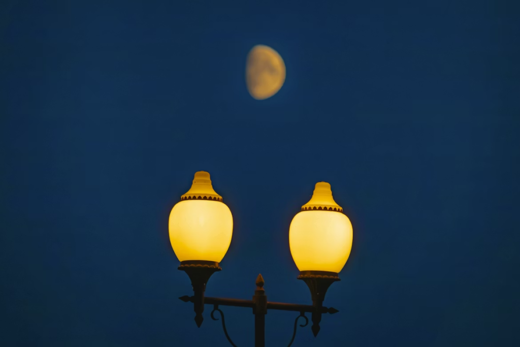 the moon behind a set of streetlamps