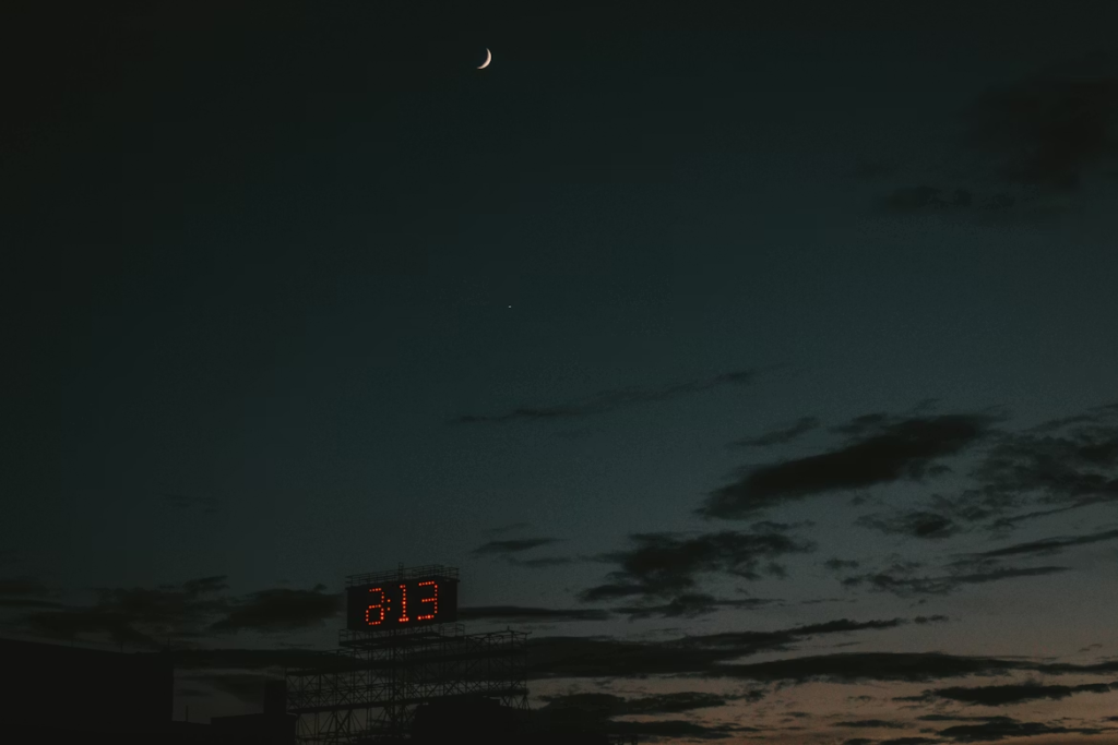 A moon rising above an inverted clock