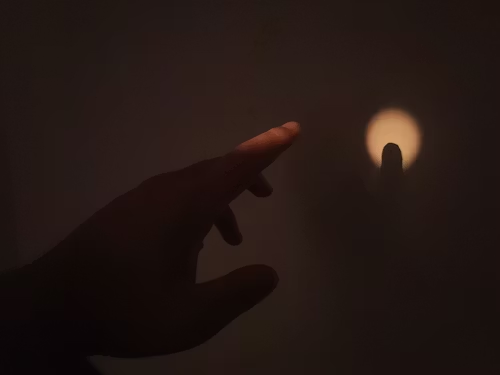 a-person-pointing-at-a-light-in-the-dark