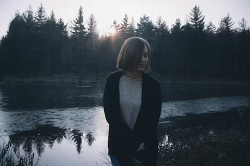 woman-in-black-cardigan-standing-by-the-lake