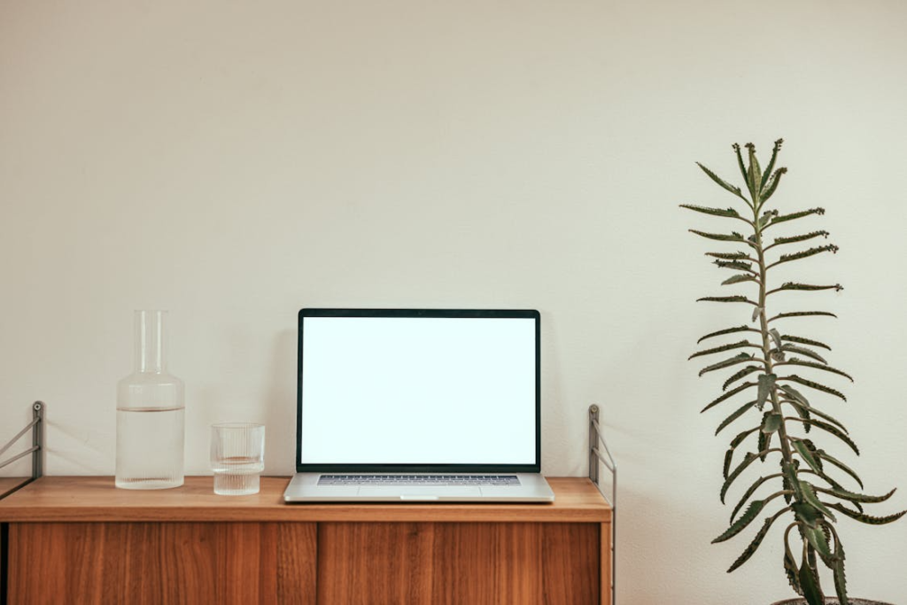 a-pitcher-and-glass-beside-a-laptop-with-white-screen
