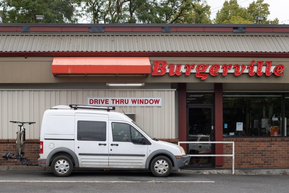 Portland, OR, USA - Aug 3, 2025: Paying and picking up takeout food at the drive thru window of a Burgerville restaurant in Portland, Oregon. Burgerville is a fast food chain owned by The Holland Inc.