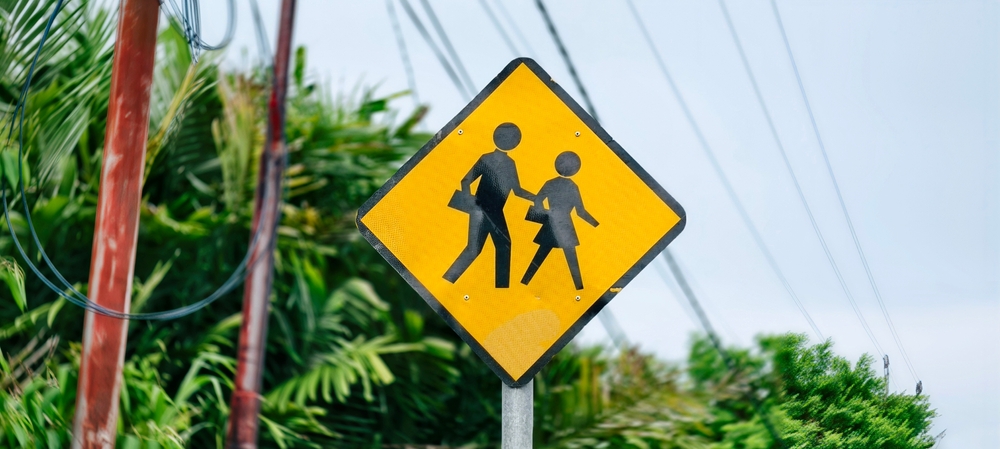 The yellow diamond-shaped traffic sign in the picture is a warning sign for a “school zone” or “children crossing.” 