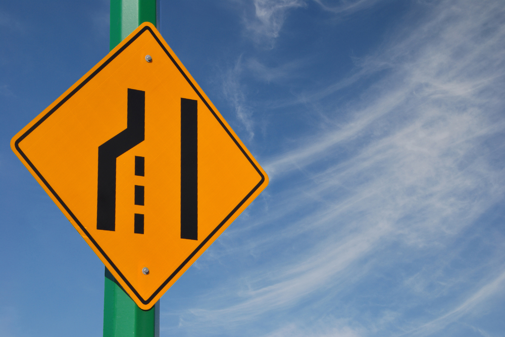 Merge left traffic sign and cloudy sky