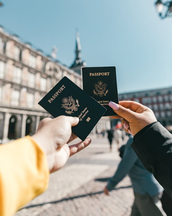 Travelers holding US passports at Plaza Mayor, Madrid, highlighting tourism and exploration.
