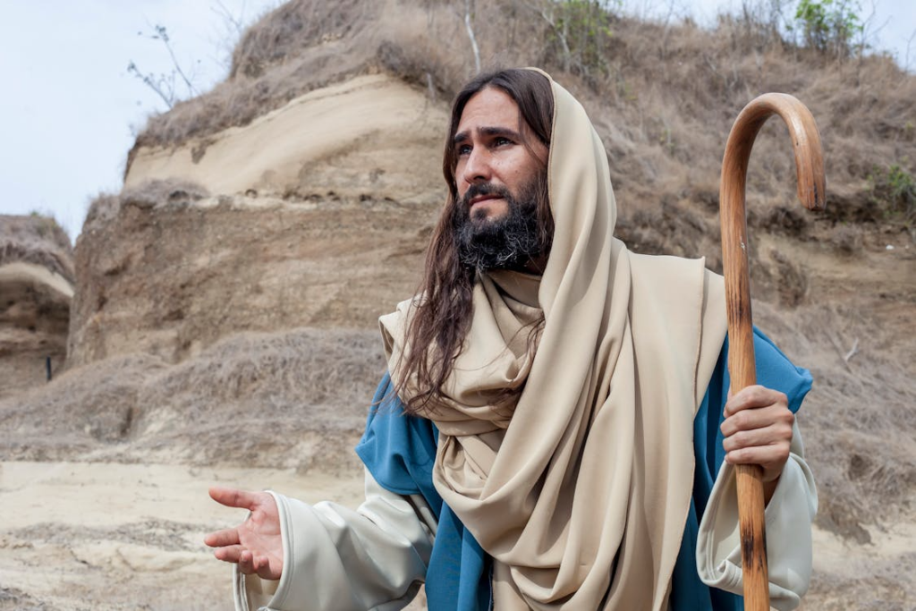A man dressed as a biblical shepherd with crook in a rustic Colombian landscape.
