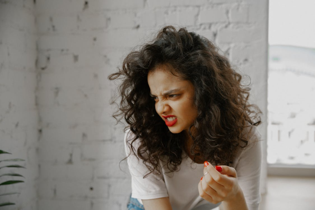 woman with red nails and curly hair making a face