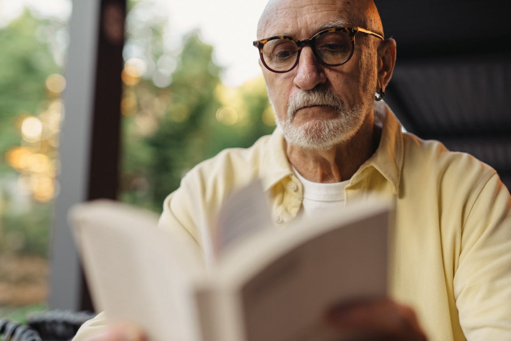Man in Yellow Long Sleeve Shirt Reading a Book
