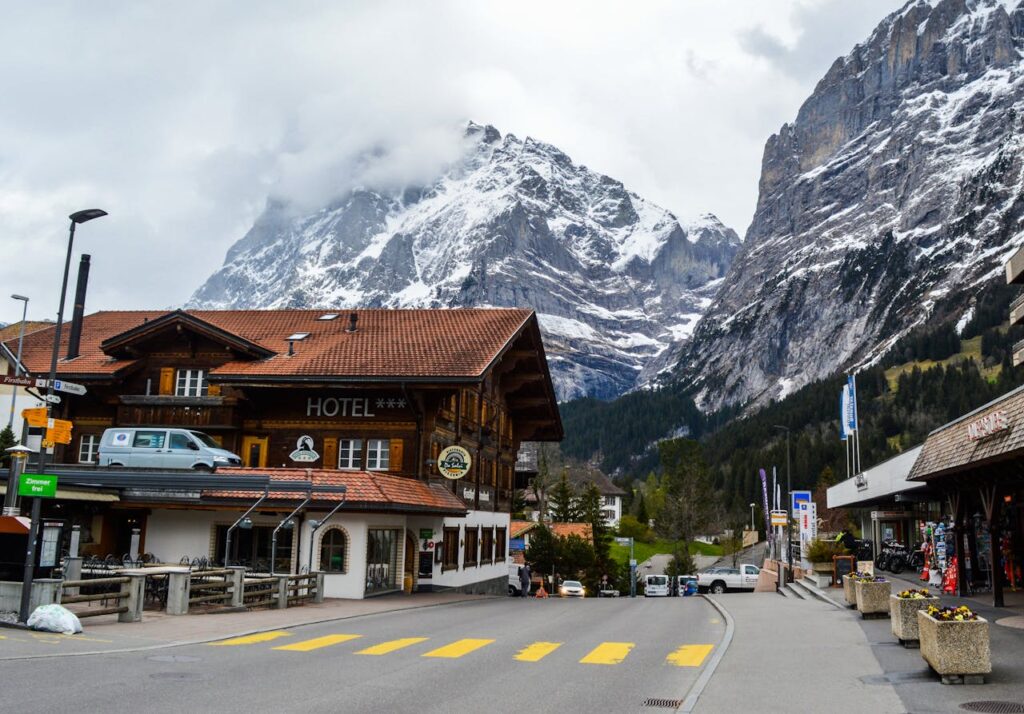 Old hotel facade near road and snowy mountains in fog
