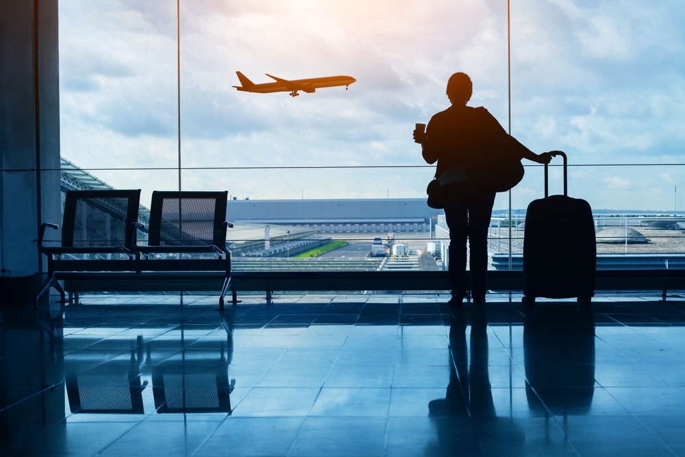 travel by plane, woman passenger waiting in airport, silhouette of passenger watching aircraft taking off

