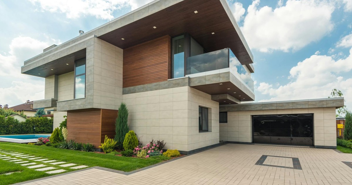 Contemporary luxury house with a sleek design, lush garden, and blue sky.