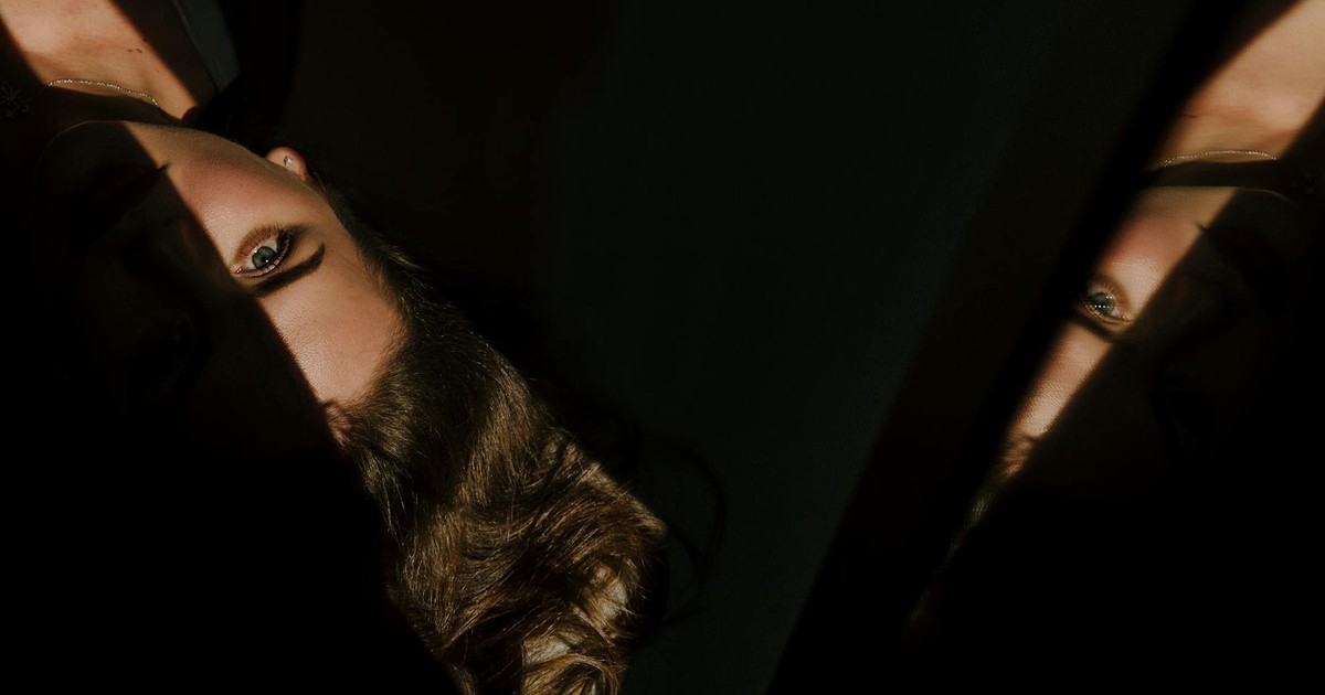 Moody portrait featuring dramatic shadows and reflections on a woman's face.