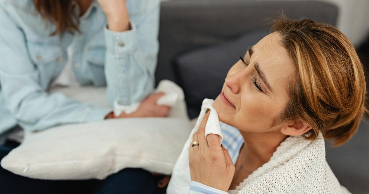 A woman crying with a napkin, comforted by a friend, expressing emotions.