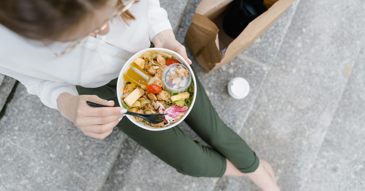 Top-down view of a woman enjoying a healthy salad outdoors during a casual lunch break.