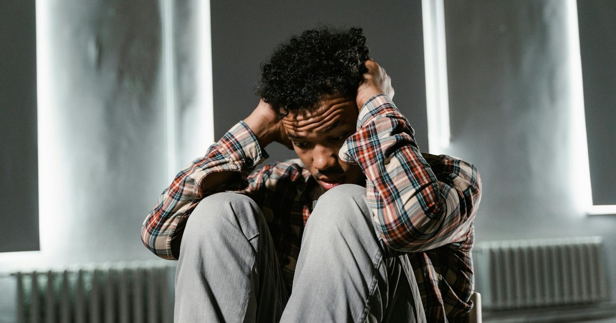 A man sitting with his hands on his head, appearing anxious and distressed.