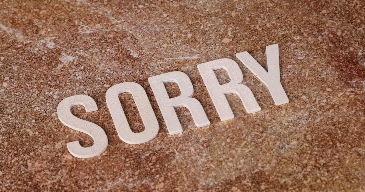 Wooden letters spelling 'SORRY' on a textured marble surface, symbolizing apology or regret.