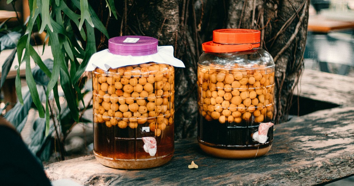 Two jars filled with preserved fruits resting on a rustic outdoor wooden table.