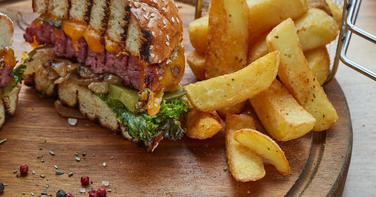 Delicious cheeseburger with cheddar and crispy fries on a wooden platter, perfect for a hearty meal.