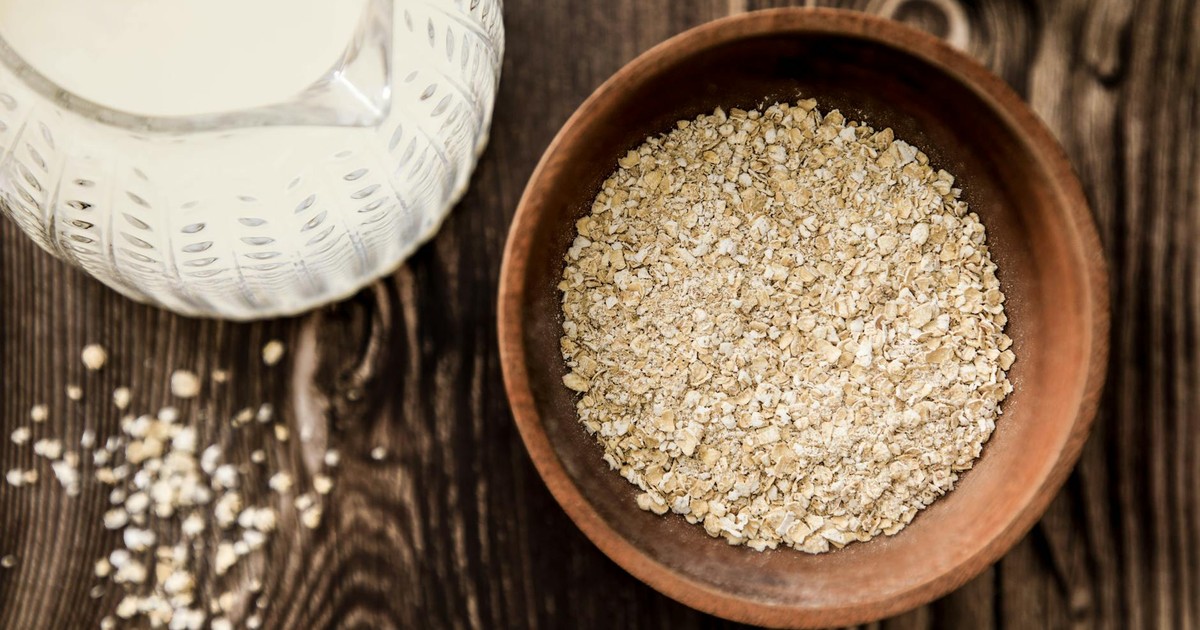 Wooden bowl of oats with milk jug on rustic table. Ideal for health-focused breakfast imagery.