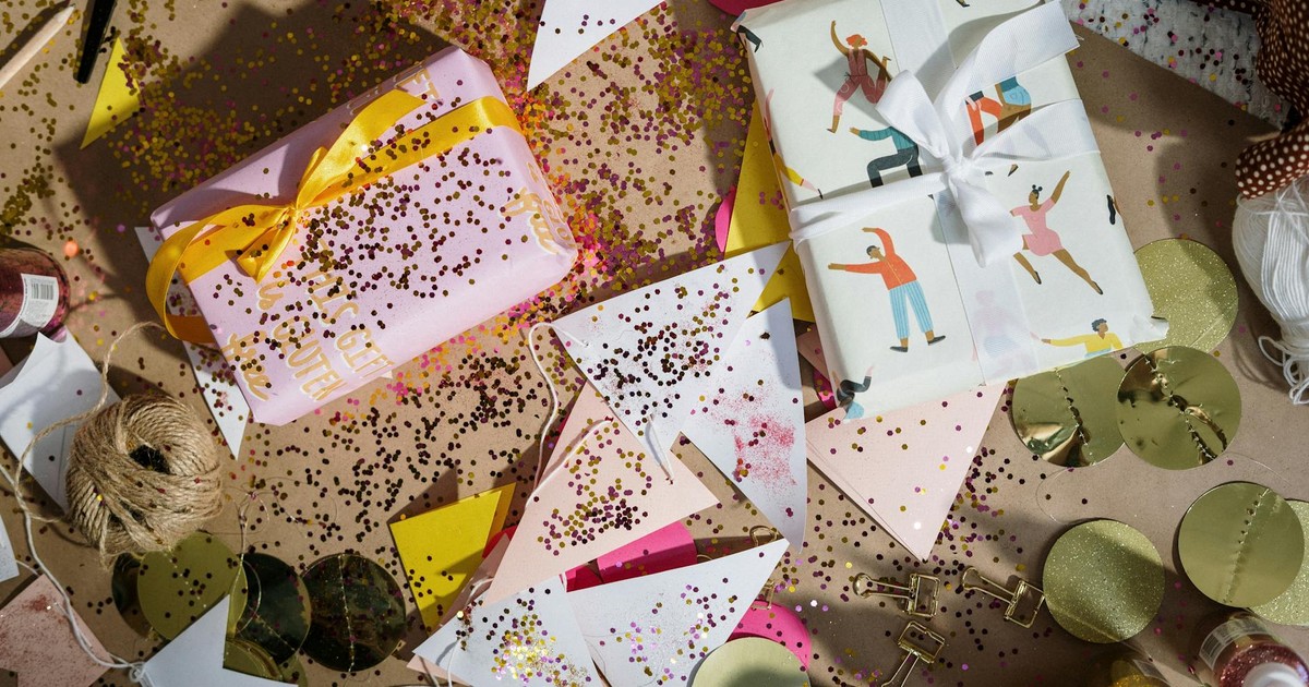 An overhead view of a festive flatlay with wrapped gifts, colorful glitter, and decorations creating a celebration vibe.